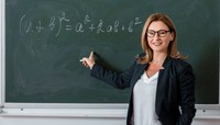 Professora escreve equações matemáticas em quadro negro.