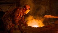 Profissional de mineração/siderurgia com equipamento de segurança atua em alto forno.