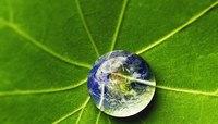 Gota de água sobre folha verde com imagem do planeta terra projetada.