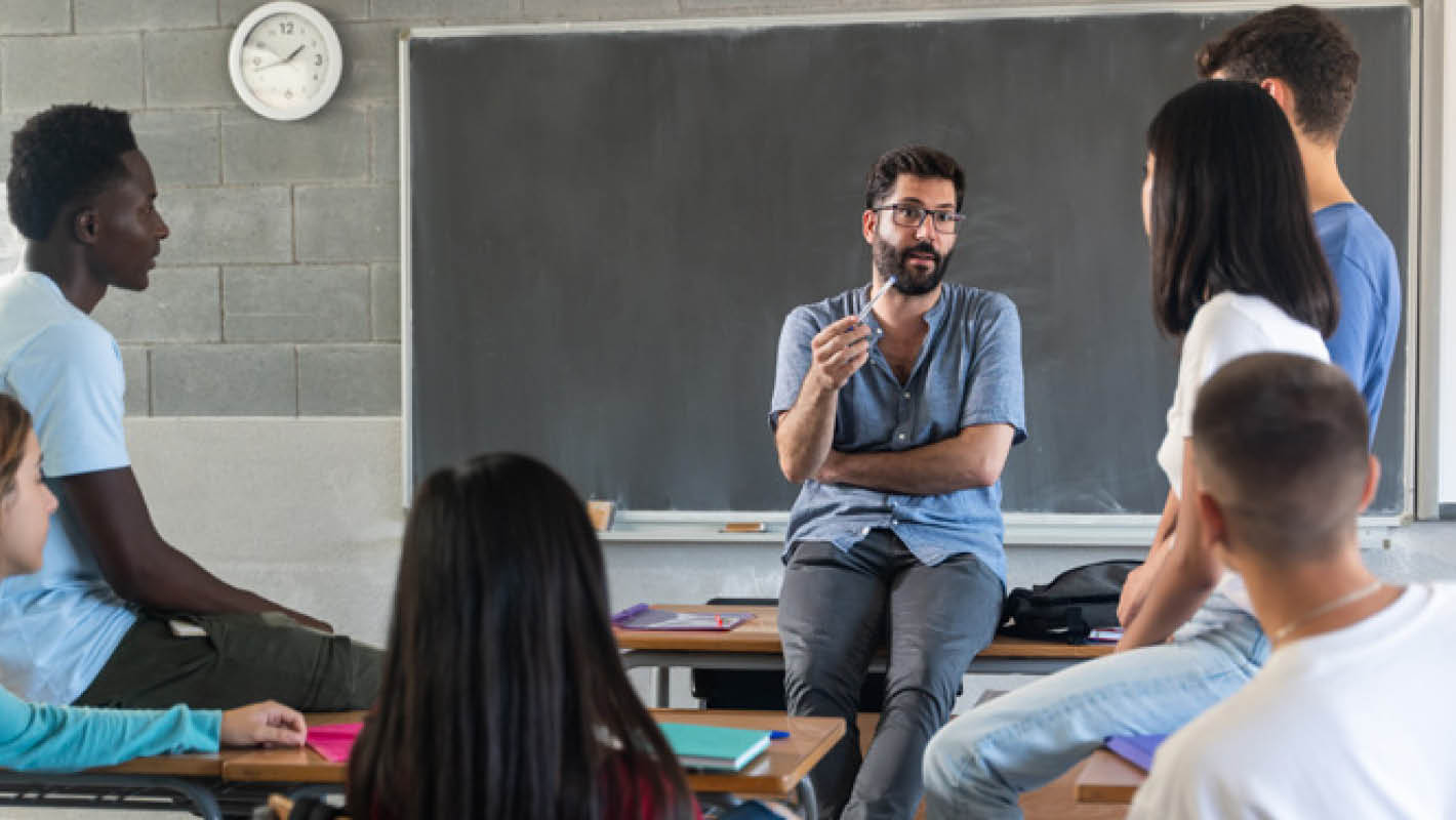 Professor interage com alunos na sala de aula.