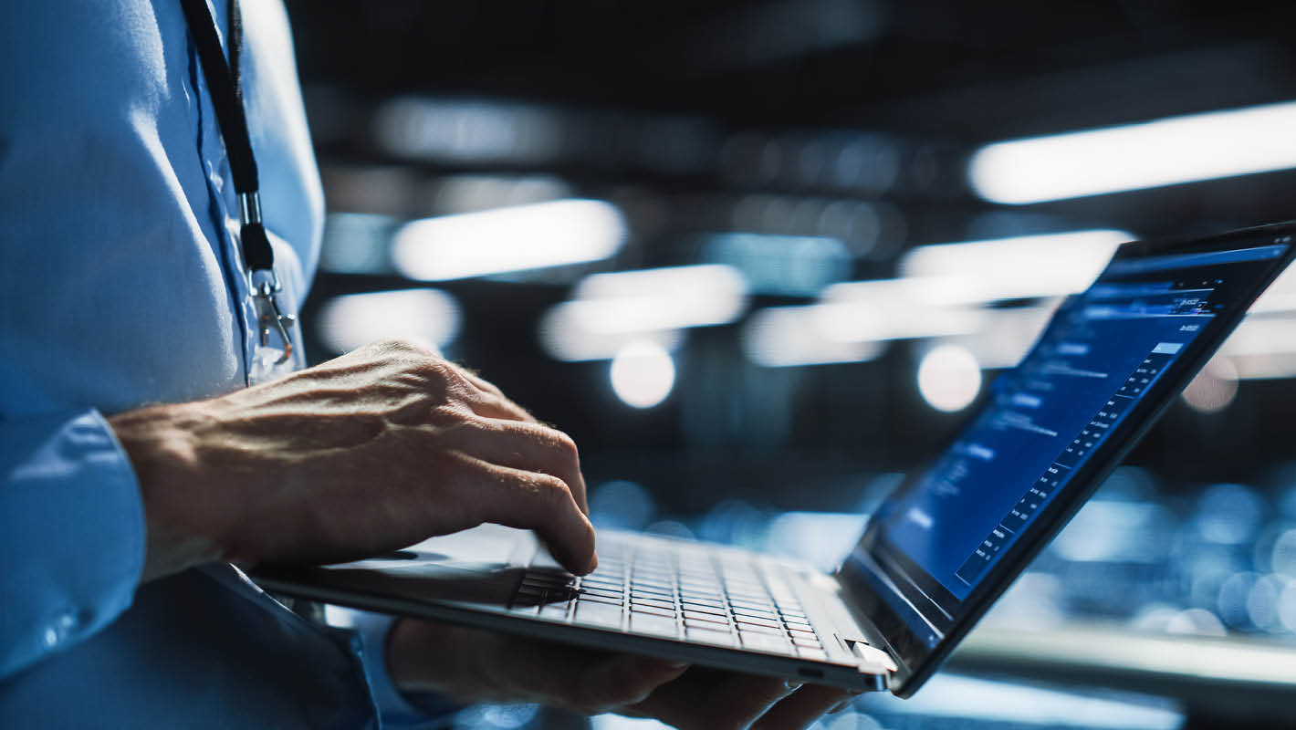 Homem com camisa social e crachá trabalha no notebook